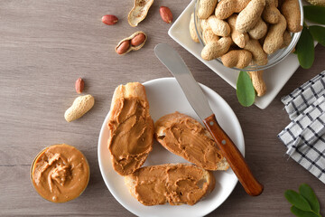 Freshly sliced ​​bread spread with peanut butter on wooden table
