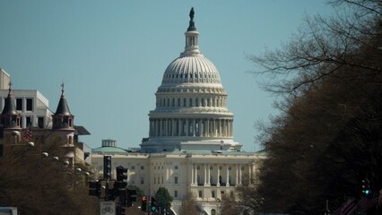 Capitol building is visible in the distance with trees along the road, shows a sunny day in Washington DC with no people around.