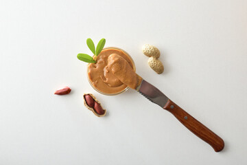 buttered knife resting on a bowl of peanut butter isolated