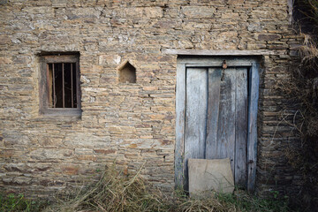 A village house made of mud and stone with wooden doors.
