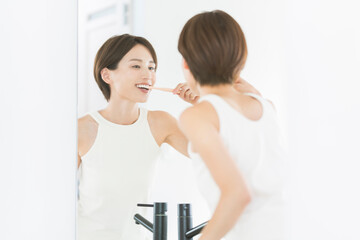 鏡を見ながら歯を磨いている女性