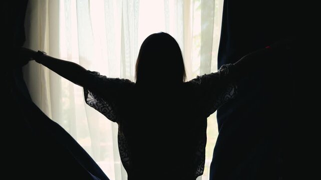  The woman pulls back the curtains and opens the morning light inside. High quality 4k footage