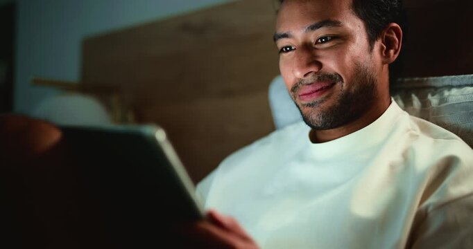 Evening, bedroom and man with tablet, reading and search for online article, social media and digital app. Doom scroll, tech or person with ebook, home or blue light exposure with internet and night