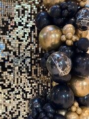 Geometric shiny metallic squares background in black, silver, gold and bronze lined on the side with gold, black and clear balloons