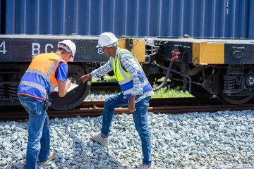 Freight train engineers inspect a railcar wheel and axle, as two railroad workers check cargo train maintenance