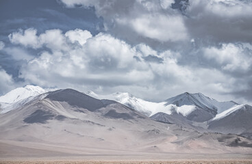 Landscape in the Pamir Mountains of Tajikistan with snow, glaciers, and cliffs, a panorama of mountains in cloudy weather for the background, nature in the Tien Shan highlands, landscape background