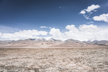 Landscape in the Pamir Mountains of Tajikistan with snow, glaciers, and cliffs, a panorama of mountains in cloudy weather for the background, nature in the Tien Shan highlands, landscape background