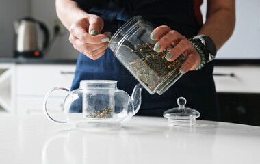 Girl Pouring Green Tea Into Teapot In The Kitchen