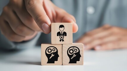 A person stacking wooden blocks with human and lightbulb illustrations on a table