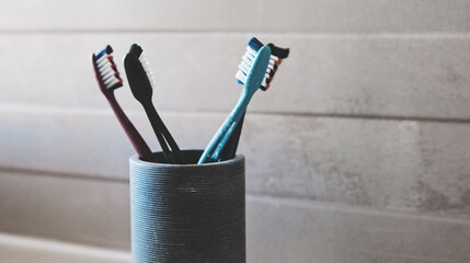 Family Toothbrushes In Bath Cup In Bathroom