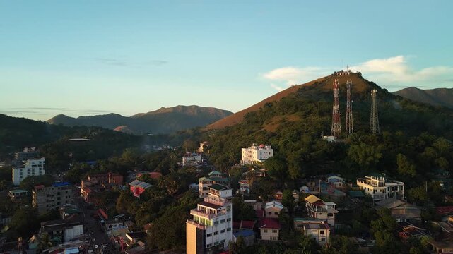 Aerial pullback from Coron Town toward Mount Tapyas with hillside homes cell towers and warm golden hour light over Busuanga Island