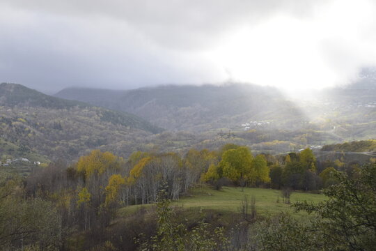 View of the landscape of rolling hills and golden leaves under a cloudy sky with soft sun rays piercing through, Posof, Ardahan, Ardahan, Turkey.