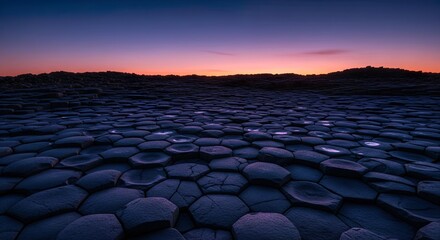Obraz premium Low-Angle Shot of Basalt Columns Forming a Symmetrical Hexagonal Pavement Under Twilight Sky