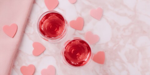 Two glasses of red wine with hearts on the table