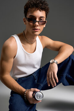 Stylish teenager exuding confidence in tank top and sunglasses against grey backdrop