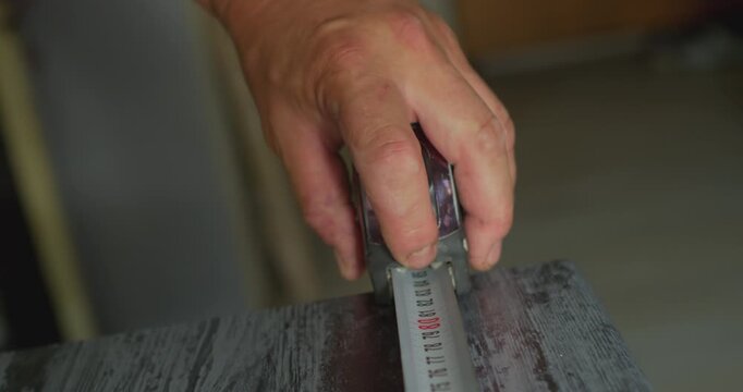 Worker using measuring tape on wooden surface
