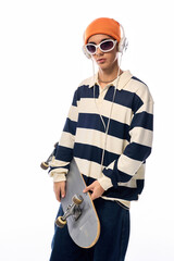 Fashionable teen with a skateboard poses against a white backdrop