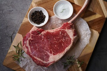 Raw uncooked Tomahawk steak with bone with salt and pepper