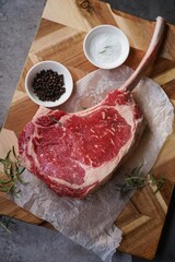 Raw uncooked Tomahawk steak with bone with salt and pepper