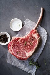 Raw uncooked Tomahawk steak with bone with salt and pepper