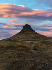 Kirkjufell mountain under a vibrant sunset sky painted in orange, red, and pink hues, creating a dramatic and colorful Icelandic landscape.