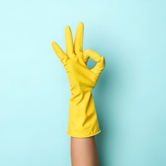 Hand in yellow rubber glove making OK gesture on a blue background.