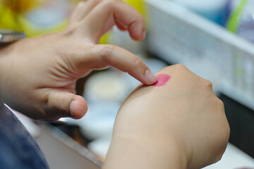 close-up of a woman's hand testing lipstick swatches