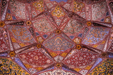 View of an intricately painted ceiling with vibrant geometric patterns and floral motifs showcasing the rich artistic heritage, Lahore, Punjab, Pakistan.
