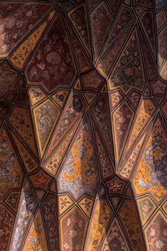 View of an ornately decorated ceiling with geometric patterns and floral designs in warm hues, creating a mesmerizing visual tapestry, Lahore, Punjab, Pakistan.