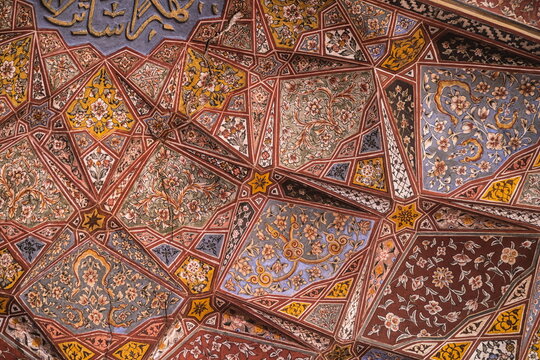 View of the intricate, geometrically patterned ceiling adorned with floral motifs and calligraphy, a testament to artistry, Lahore, Punjab, Pakistan.
