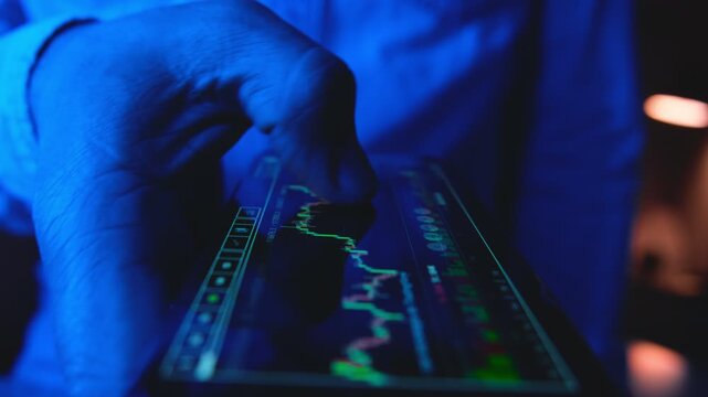 Close-up of a businessman's hand checking a financial stock market graph on a mobile device