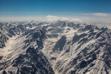 Aerial view of snow-capped mountains under a clear sky creates a stark contrast against the rugged terrain, Skardu, Gilgit Baltistan, Pakistan.