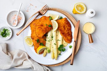 White asparagus with fried schnitzel, lemon and hollandaise sauce