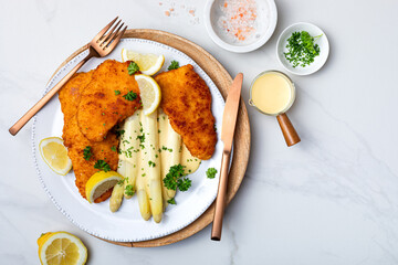 White asparagus with fried schnitzel, lemon and hollandaise sauce