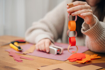 Hands making a paper craft (origami or decoration) on a wooden table, focusing on creativity and manual skill