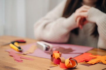 Hands making a paper craft (origami or decoration) on a wooden table, focusing on creativity and manual skill
