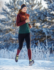 A woman jogging in winter, with a winter landscape in the background.