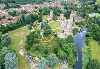Aerial view of Warwick Castle's ancient stone walls and lush green grounds meet the tranquil Avon River, a tapestry of history and nature, Warwick, Warwickshire, England.