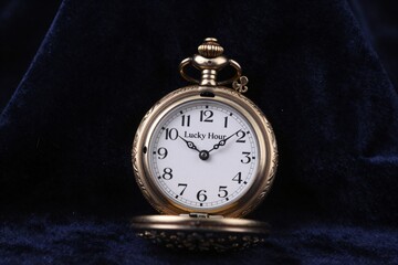 Vintage gold pocket watch on velvet with roman numerals and ornate details