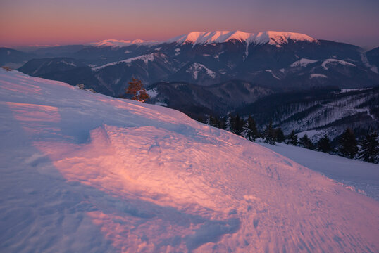 View of snow-covered terrain kissed by the warm glow of the rising sun, with majestic mountains in the distance, Nova hola, Banskobystricky kraj, Slovakia.