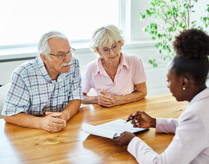 Happy senior old family couple clients make financial insurance estate business deal contract signing, agent lawyer, satisfied mature customers signing contract meeting bank manager agree on investmen