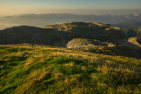Aerial view of Tosc capturing the golden hour's glow on the rugged peaks and verdant slopes, Gorenjska, Julian Alps, Slovenia.