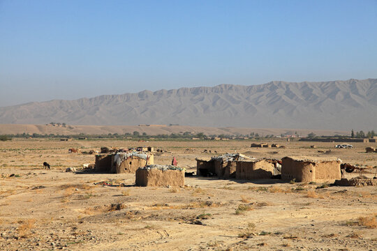View of sun-baked mud houses scatter across the arid landscape, under a vast sky, with distant mountains adding a rugged backdrop, Quetta, Balochistan, Pakistan.