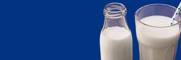 Fresh white milk in glass bottle and drinking glass with straw