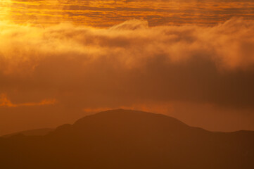 Aerial view of fiery skies meet the silhouette of mountainous terrain, a dance of light and shadow over the horizon, Western Tatras, Zilinsky kraj, Slovakia.