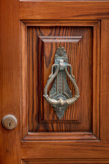 A beautifully detailed wooden door featuring an ornate knocker, reflecting the local craftsmanship