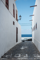 Garachico, Tenerife, Spain, A narrow alleyway leading to the sea, framed by whitewashed walls and a bright blue sky