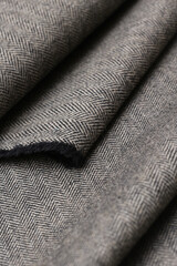 Close-up view of classic English tweed wool fabric in a fine gray and black herringbone weave....