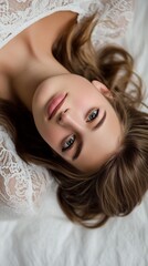 Naklejka premium Intimate portrait of a woman with soft makeup and wavy hair, lying on delicate white lace fabric with a contemplative gaze