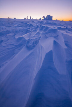 View of a snow-covered landscape with sculpted drifts under a pastel dawn sky, creating a serene winter scene, Velka Hola, Banska Bystrica Region, Slovakia.